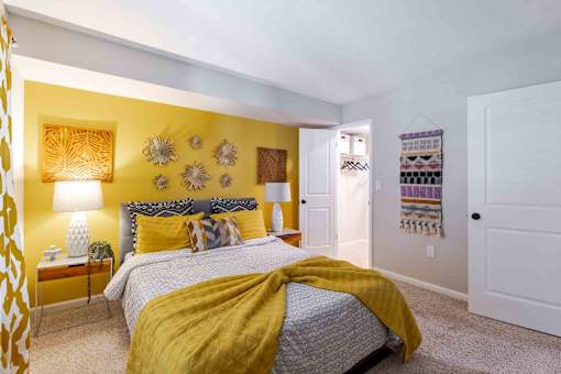 A bedroom with a bed covered in a yellow blanket.