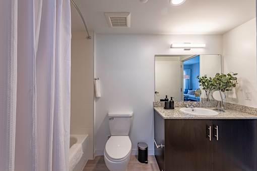 A bathroom with a toilet, sink, and mirror.