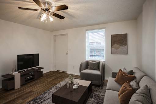 A living room with a grey couch, a brown coffee table, and a ceiling fan.