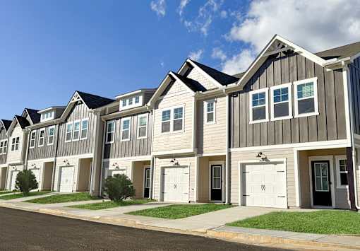A row of houses with white garage doors and black shutters.