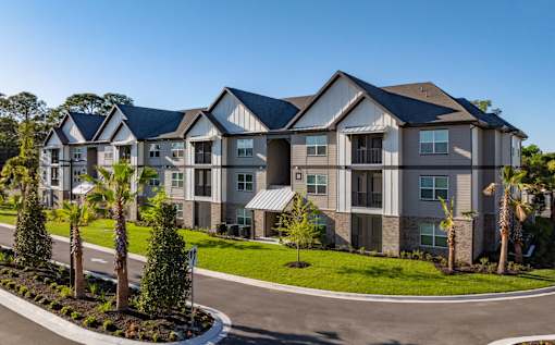 A large, modern apartment complex with a well-maintained lawn and landscaping.