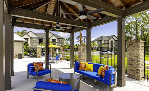 A patio with blue couches and a ceiling fan.