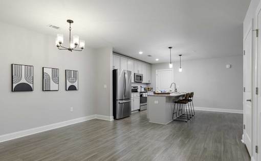 A kitchen with a dining table and chairs is visible through an open door.