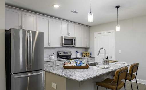 A modern kitchen with a stainless steel refrigerator and a granite countertop.