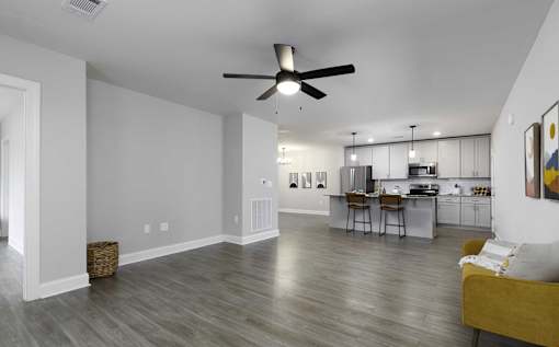 A spacious living room with a kitchen in the background.