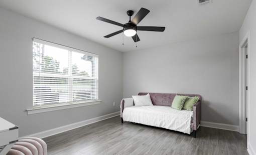 A living room with a white couch and a ceiling fan.