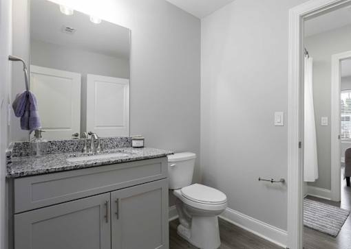 A bathroom with a toilet, sink, and mirror.