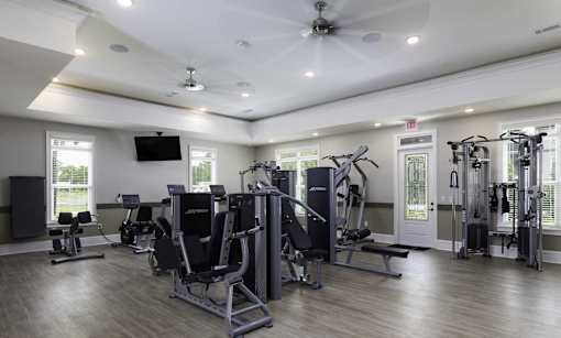 A spacious gym with a variety of equipment and a flat screen TV mounted on the wall.