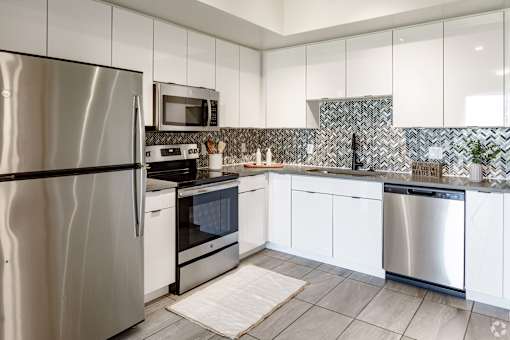 A modern kitchen with stainless steel appliances and white cabinets at Saba Pompano Beach, Pompano Beach, 33062