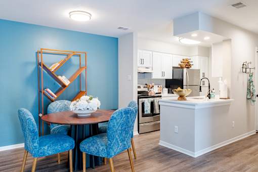 A dining room with a round table and blue chairs.