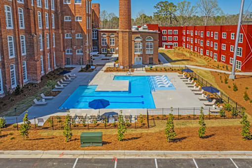 A large swimming pool surrounded by red brick buildings.