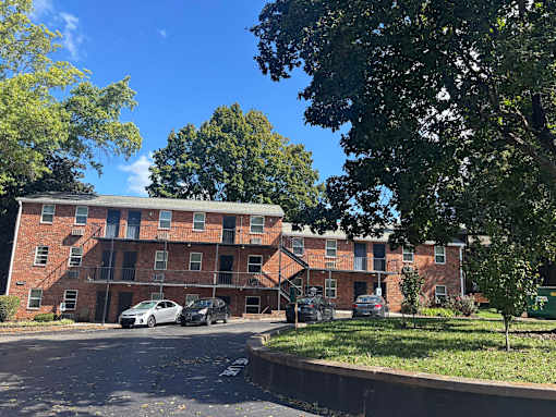 A red brick apartment building with cars parked in front.
