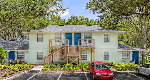 A two-story house with a red car parked in front.