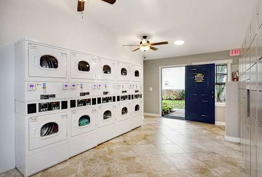 A laundry room with a row of washers and dryers.