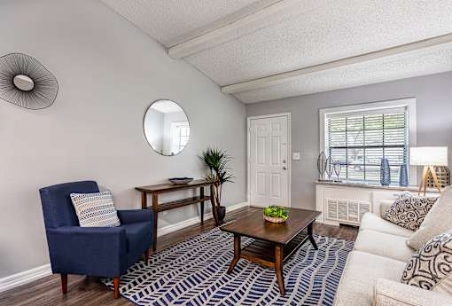 A living room with a blue armchair, a wooden coffee table, and a white sofa.