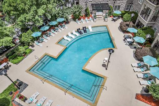 A large outdoor swimming pool surrounded by lounge chairs and umbrellas.