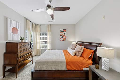 A bedroom with a bed, dresser, and ceiling fan.