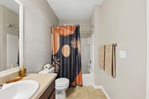 A bathroom with a sink, toilet, and shower curtain.