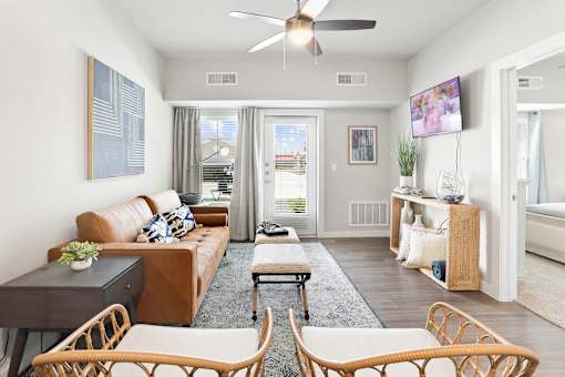 A living room with a brown couch and a ceiling fan.