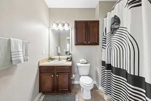 A bathroom with a sink, toilet, and a shower curtain with black and white stripes.