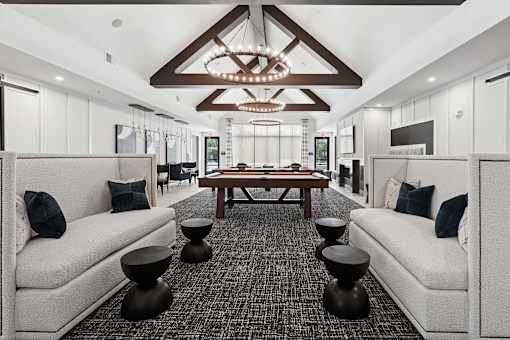 A modern living room with a large wooden table and two white couches.
