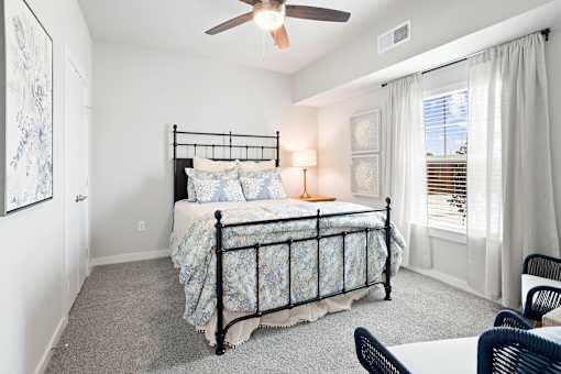A bedroom with a bed, chair, and window.