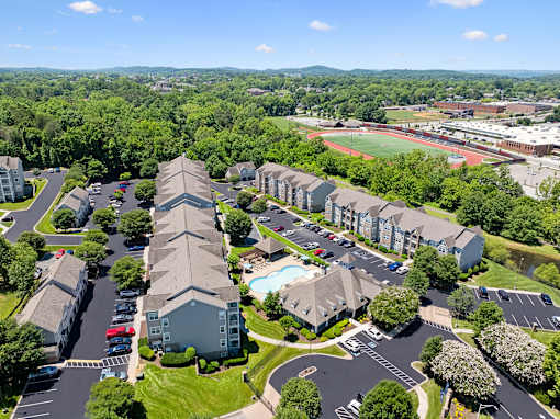 A view of a residential area with apartment buildings, a swimming pool, and a sports field.