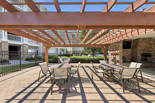 A patio with a table and chairs under a wooden pergola.