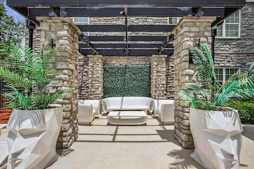 A patio with white chairs and a stone wall.