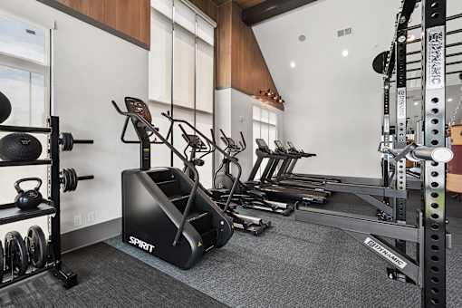 A gym with a variety of equipment including a treadmill, rowing machine, and weights.