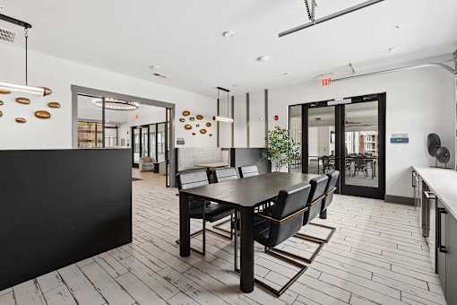 A black dining table with four chairs is in the middle of a room with white walls.