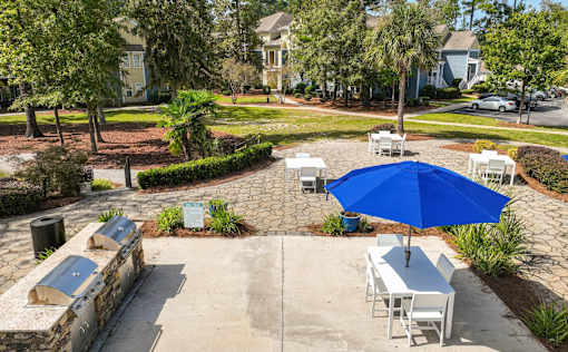 A blue umbrella is on a table in the middle of a courtyard.