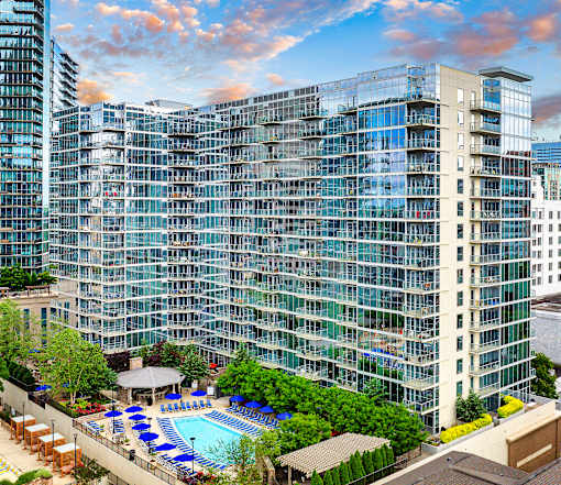 A large glass building with a pool in front.