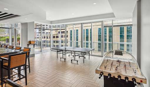 A room with a foosball table and a view of the city.
