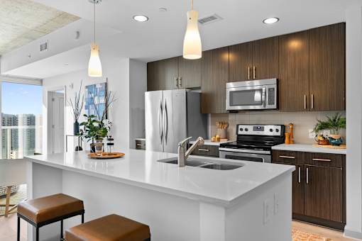 A modern kitchen with a white countertop and brown stools.