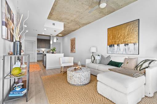 A living room with a white couch and a painting on the wall.
