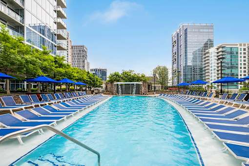 A long rectangular pool with blue water and white poolside chairs.