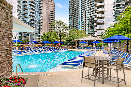 A pool with blue umbrellas and chairs.