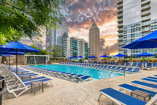 A pool area with blue umbrellas and chairs.