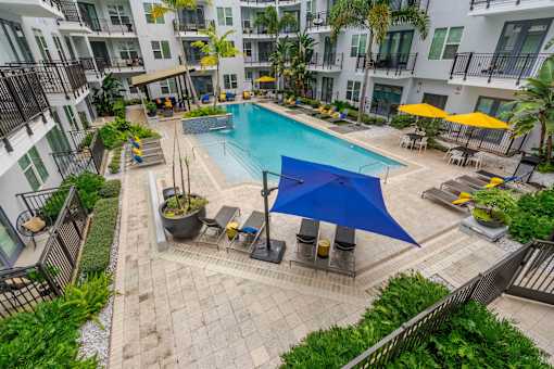A blue umbrella is on the patio of a pool.