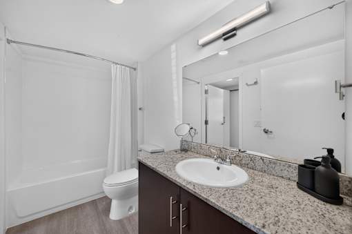 A white bathroom with a toilet, sink, and mirror.