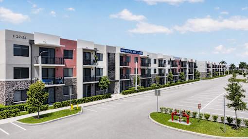 A row of modern apartment buildings with balconies and a clear blue sky above.
