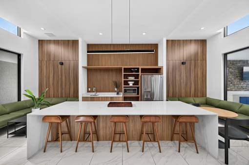 A modern kitchen with a bar area and wooden stools.