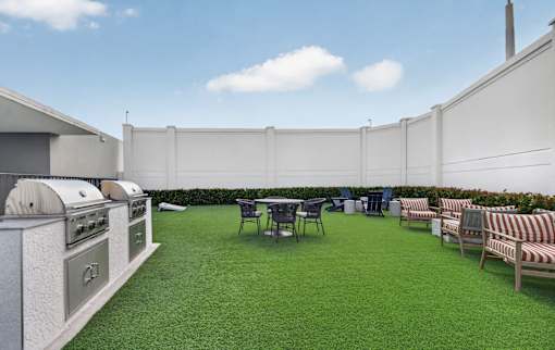A patio with a table and chairs and a grill.