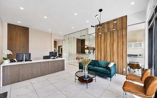 A modern living room with a green sofa and a glass wall.