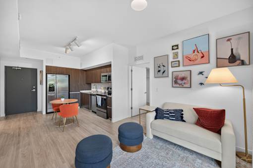 A living room with a white couch and a blue ottoman.