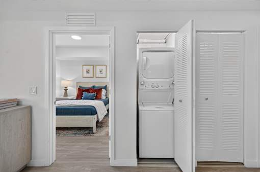 A white room with a bed and a washing machine.