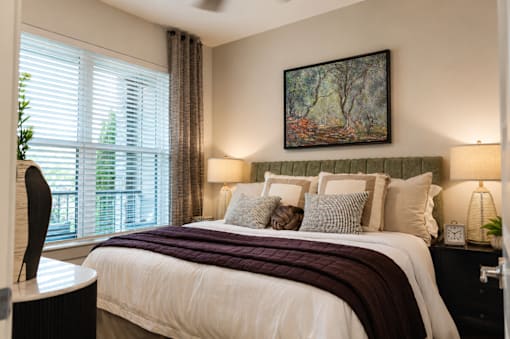 A bedroom with a large bed and a painting on the wall.