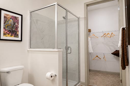 A bathroom with a toilet, a shower with a glass door, and a towel hanging on a rack.