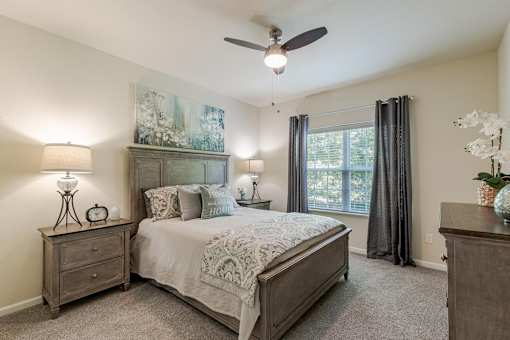 A bedroom with a bed, nightstand, and a painting on the wall.